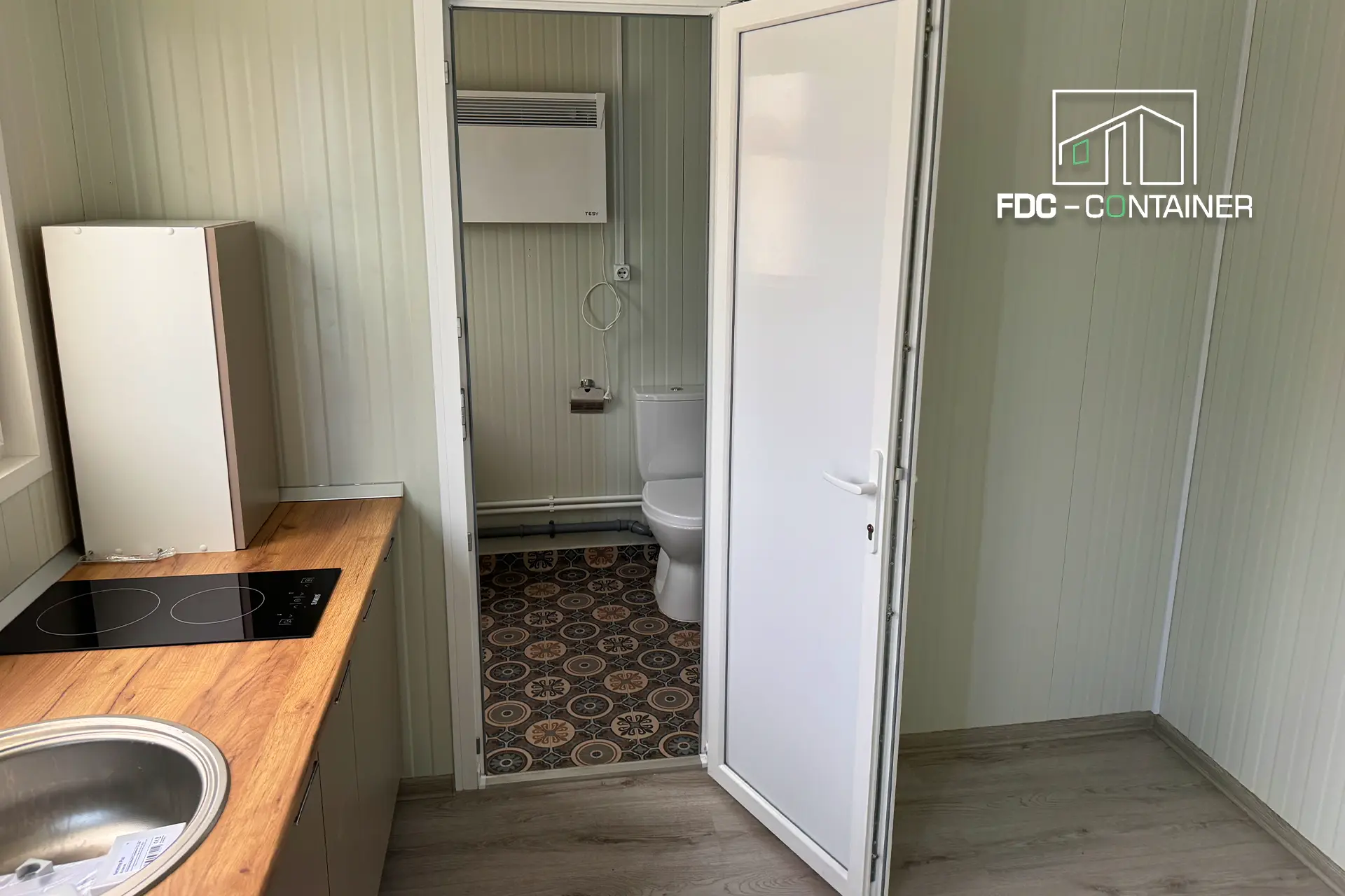 Blick ins Bad des Containers mit WC, Dusche und gemustertem Fliesenboden – FDC Container Blick ins Bad des Containers mit WC, Dusche und gemustertem Fliesenboden – FDC Container