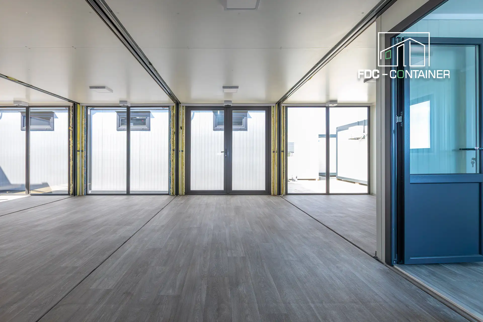 Bürocontainer innen mit Fensterfront und Empfangsbereich, Parkettoptik-Boden – FDC Container Bürocontainer innen mit Fensterfront und Empfangsbereich, Parkettoptik-Boden – FDC Container