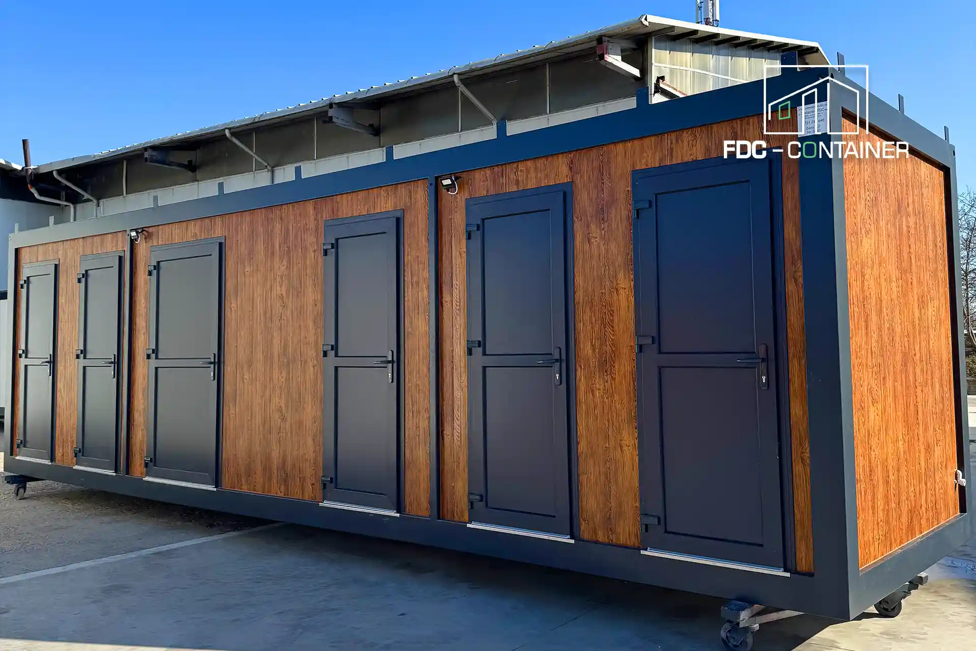 Duschcontainer fürs Camping in Holzoptik mit Kabinentüren, Außenansicht – FDC Container Duschcontainer fürs Camping in Holzoptik mit Kabinentüren, Außenansicht – FDC Container
