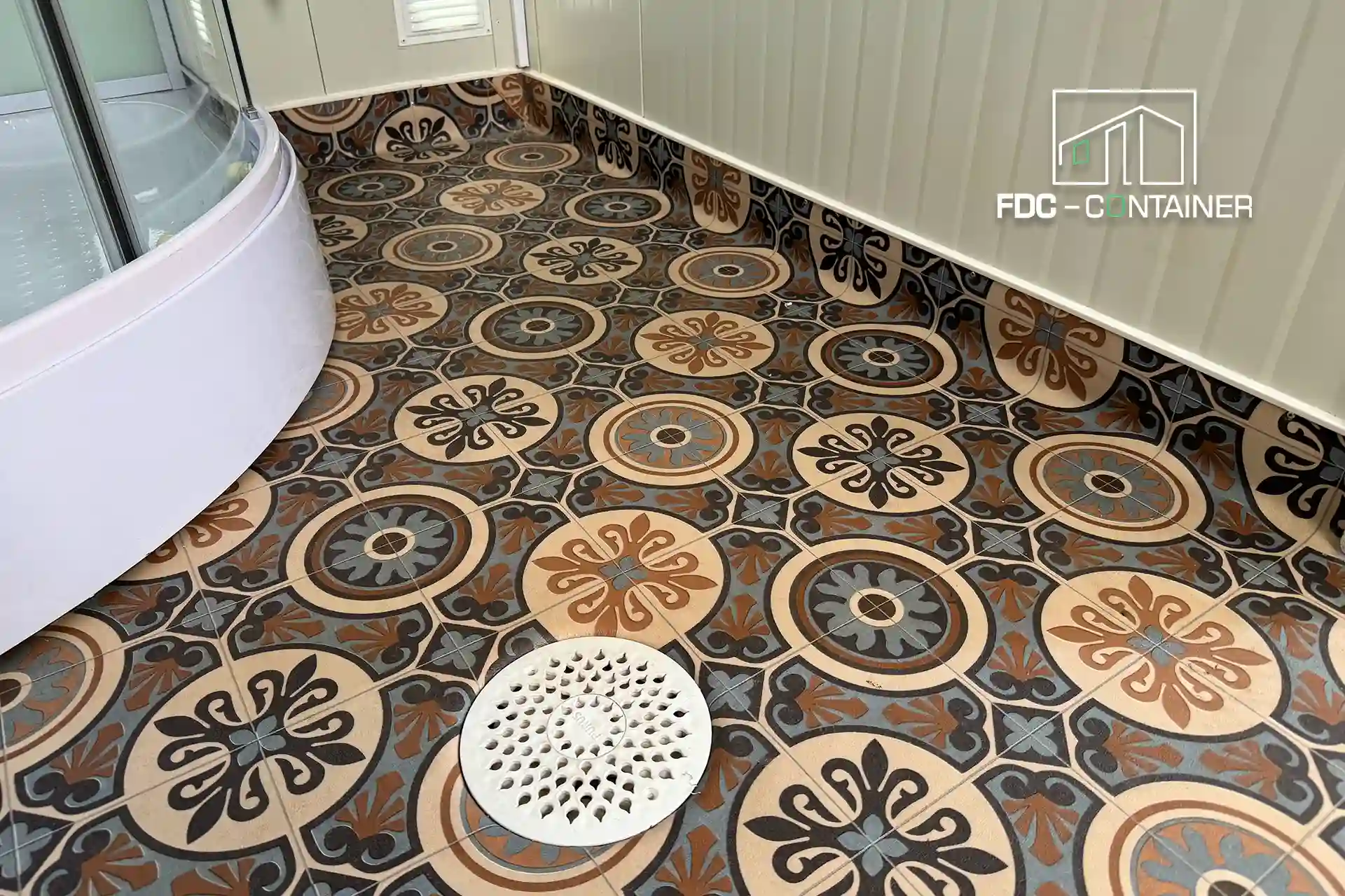 Gemusterter Mosaikboden mit Bodenablauf im Bad des Containers, Nahansicht – FDC Container Gemusterter Mosaikboden mit Bodenablauf im Bad des Containers, Nahansicht – FDC Container