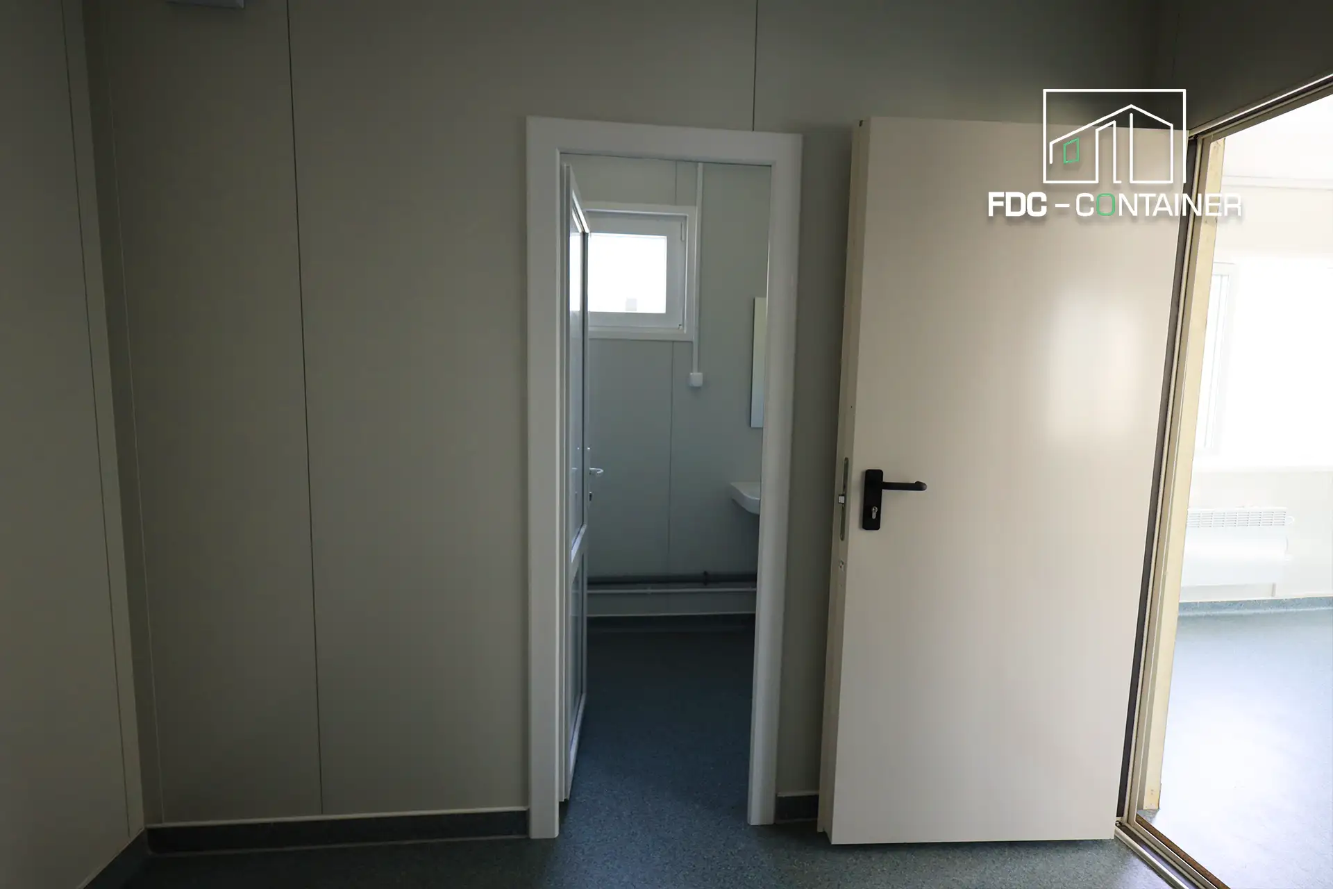 Geöffnete Tür zum Sanitärraum mit WC im Baustellencontainer – FDC Container Geöffnete Tür zum Sanitärraum mit WC im Baustellencontainer – FDC Container