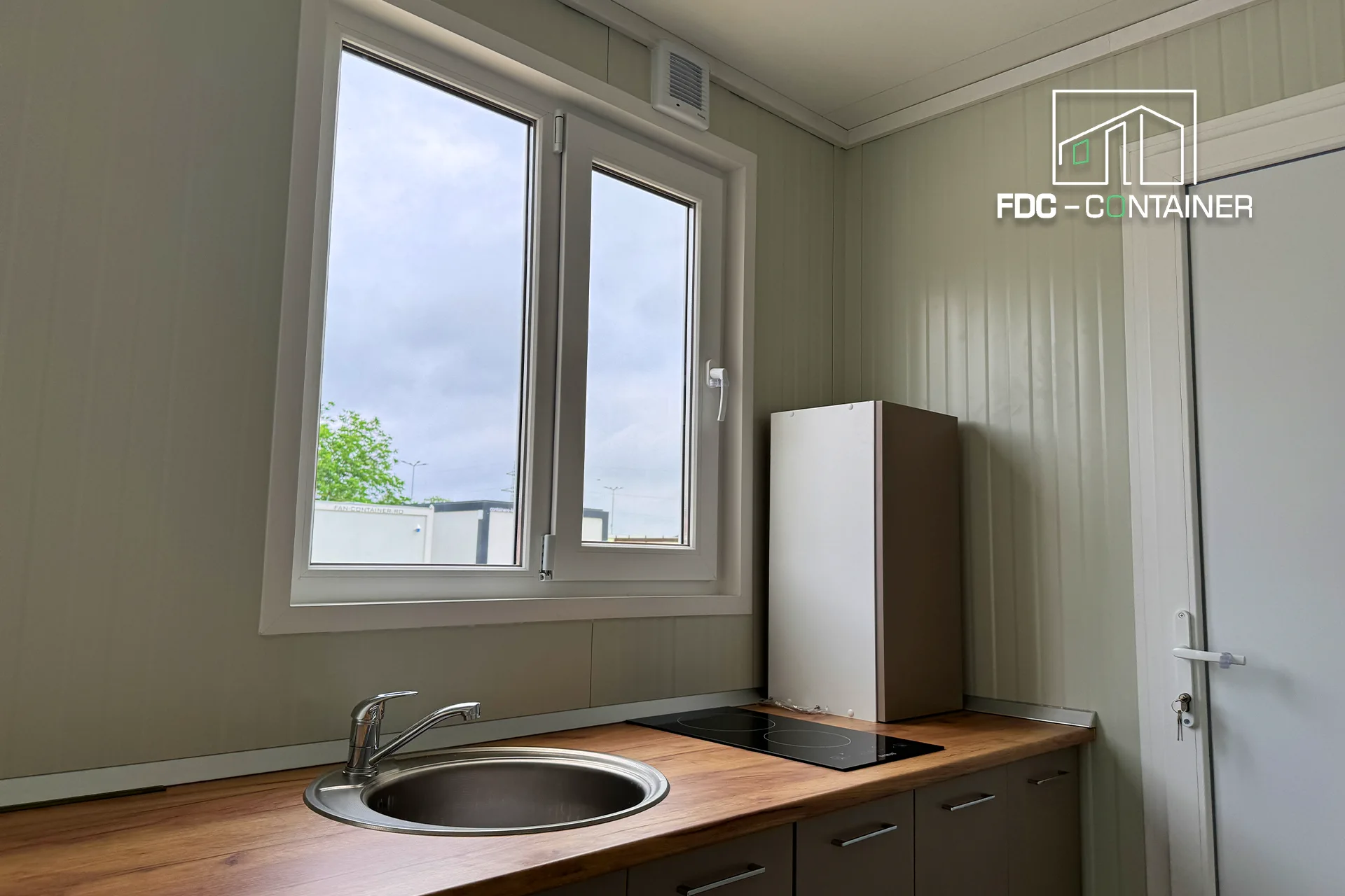 Küchenzeile mit Rundspüle und Kochfeld, Blick zum Bad im Container – FDC Container Küchenzeile mit Rundspüle und Kochfeld, Blick zum Bad im Container – FDC Container